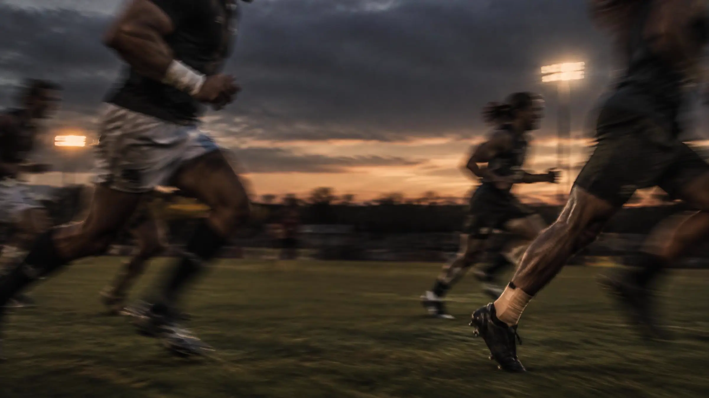 Athletes sprinting at dusk with sports strapping on wrist and ankle
